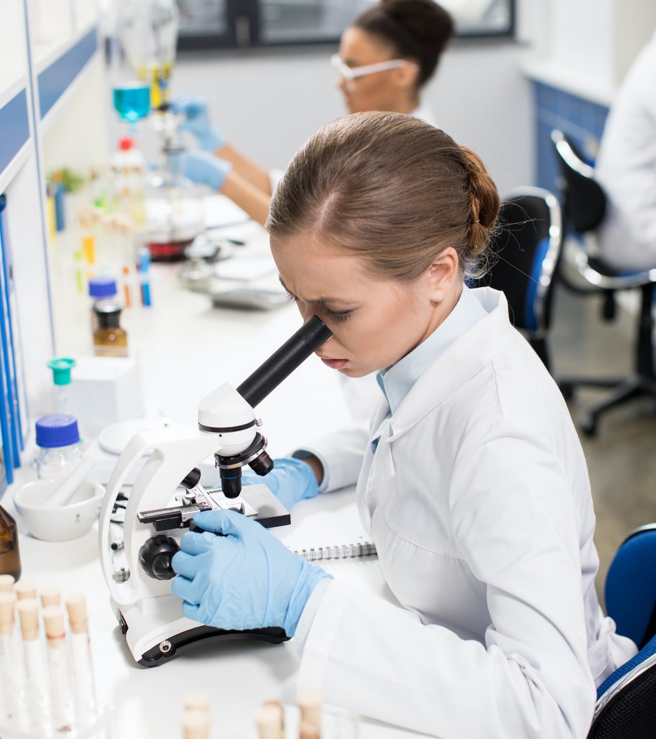 focused-young-scientist-working-with-microscope-in-research-laboratory
